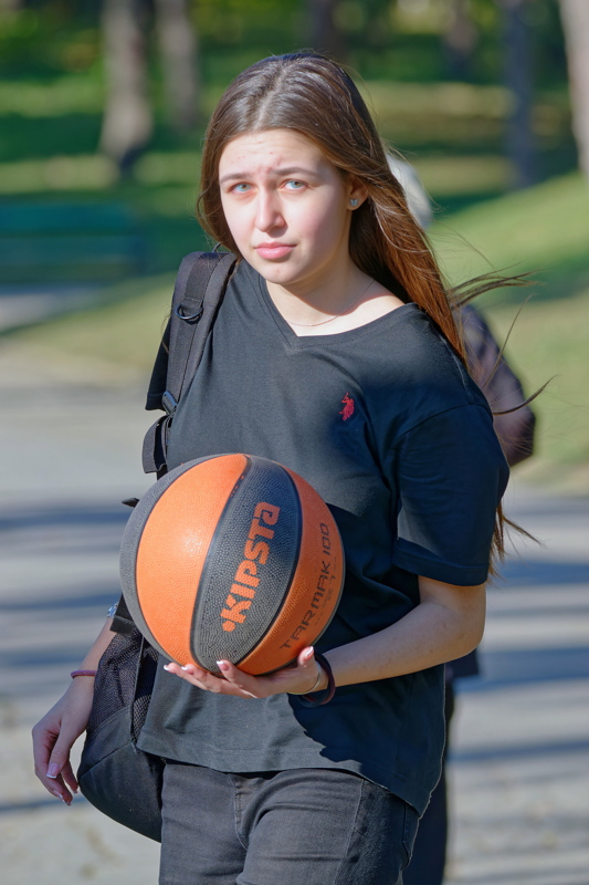 15 - An individual holding an outdoor basketball while wearing casual clothing